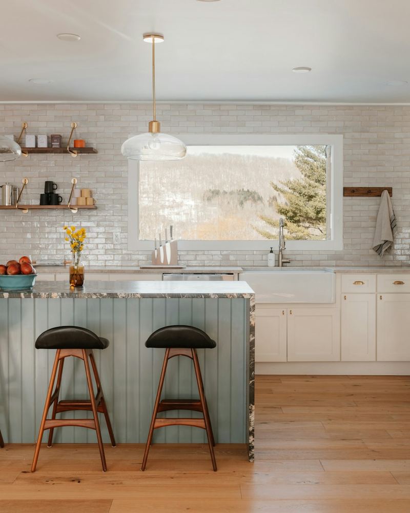 Renovated kitchen with white cabinets, subway tile backsplash and a blue-gray island with bar stools
